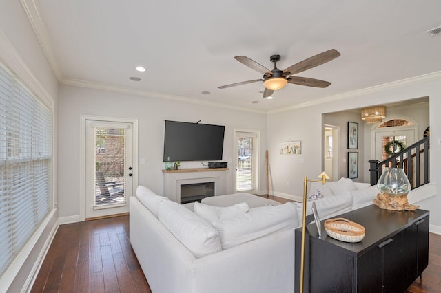 living area with a fireplace, dark wood finished floors, visible vents, ornamental molding, and baseboards