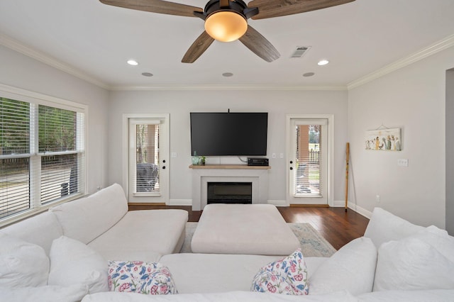 living room featuring baseboards, visible vents, dark wood-type flooring, and crown molding