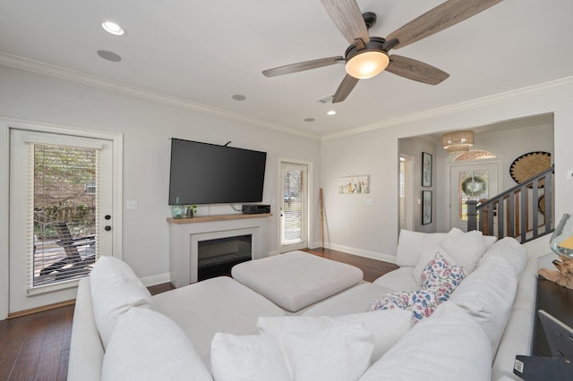 living room with baseboards, dark wood finished floors, crown molding, and a glass covered fireplace