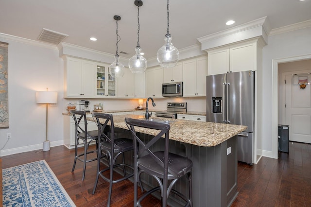 kitchen featuring stainless steel appliances, glass insert cabinets, white cabinets, an island with sink, and light stone countertops