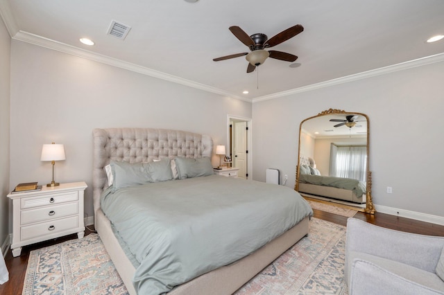 bedroom featuring baseboards, crown molding, visible vents, and wood finished floors