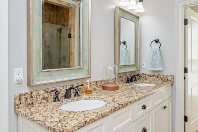 bathroom featuring double vanity, tiled shower, and a sink