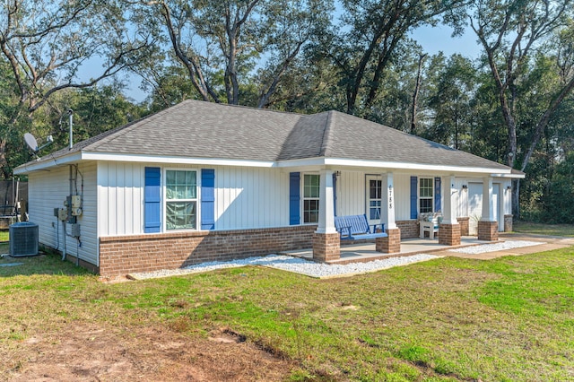 view of front of house with covered porch, central AC, a front yard, and a garage