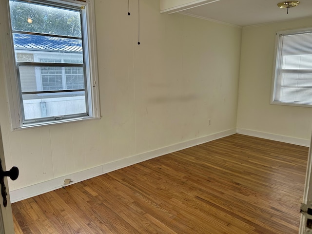 spare room with a healthy amount of sunlight, baseboards, wood finished floors, and ornamental molding