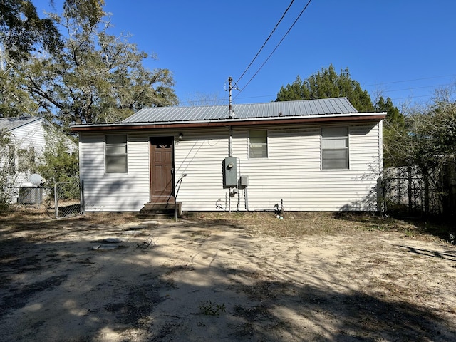 rear view of house with entry steps, fence, and metal roof