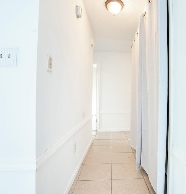 hall with baseboards and light tile patterned floors