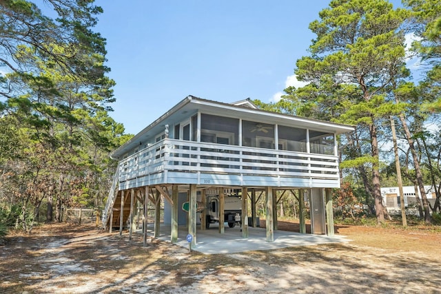 view of front facade with driveway, a sunroom, stairway, and a carport