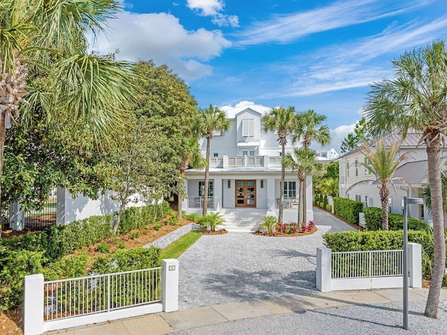 view of front of home featuring covered porch, french doors, a balcony, and a fenced front yard