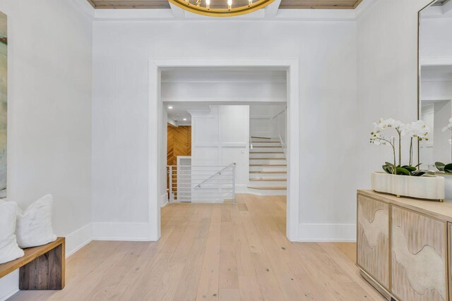 hall with light wood-style floors, baseboards, and stairway