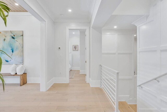 hall with light wood-style floors, recessed lighting, ornamental molding, and baseboards