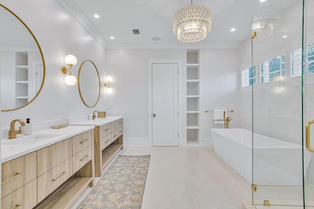 bathroom featuring built in shelves, a shower stall, two vanities, a freestanding tub, and a chandelier