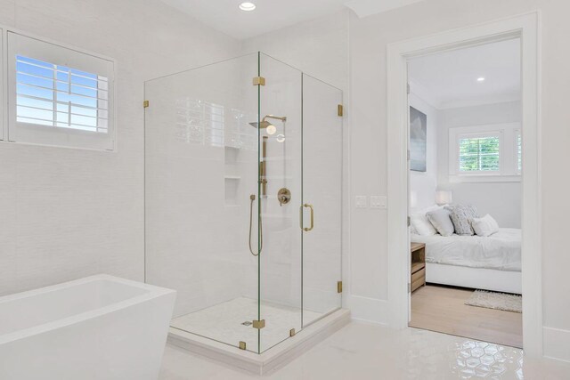 ensuite bathroom with a stall shower, a freestanding tub, and recessed lighting