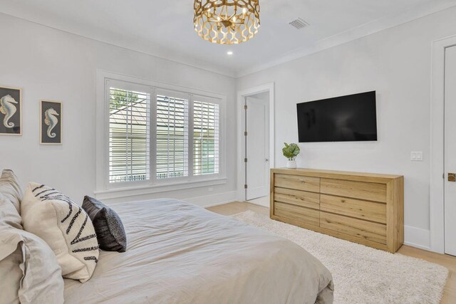 bedroom with a chandelier, baseboards, wood finished floors, and ornamental molding