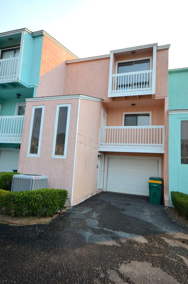 view of building exterior featuring central air condition unit, an attached garage, and aphalt driveway