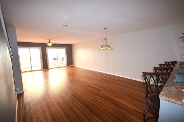 unfurnished living room featuring dark wood-style floors, visible vents, baseboards, and a ceiling fan