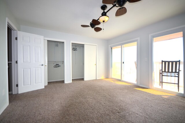 unfurnished bedroom with carpet floors, a ceiling fan, baseboards, and two closets