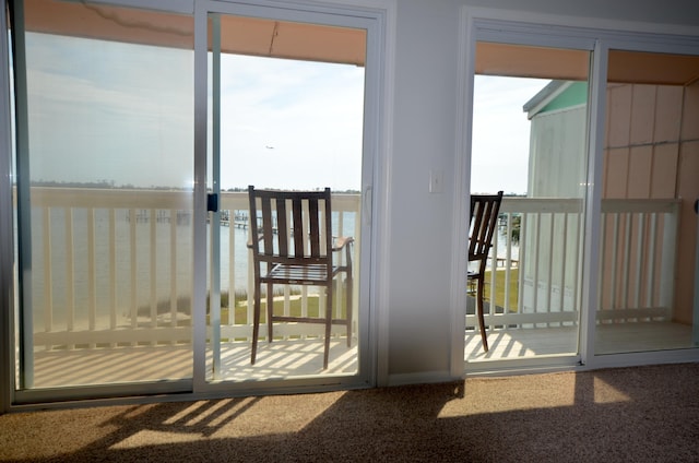 doorway to outside with a water view and carpet flooring