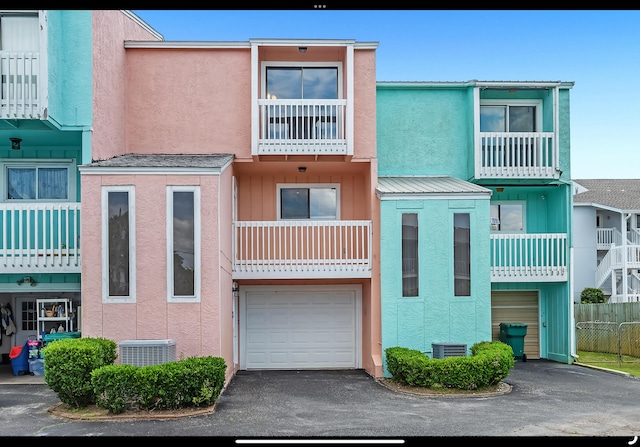 view of property with a garage, central AC unit, and aphalt driveway