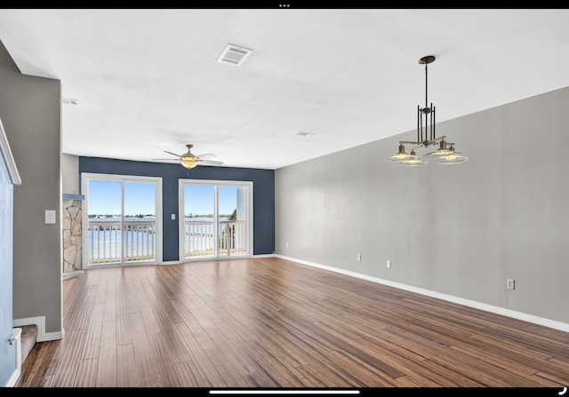 unfurnished living room featuring a water view, baseboards, visible vents, wood finished floors, and ceiling fan