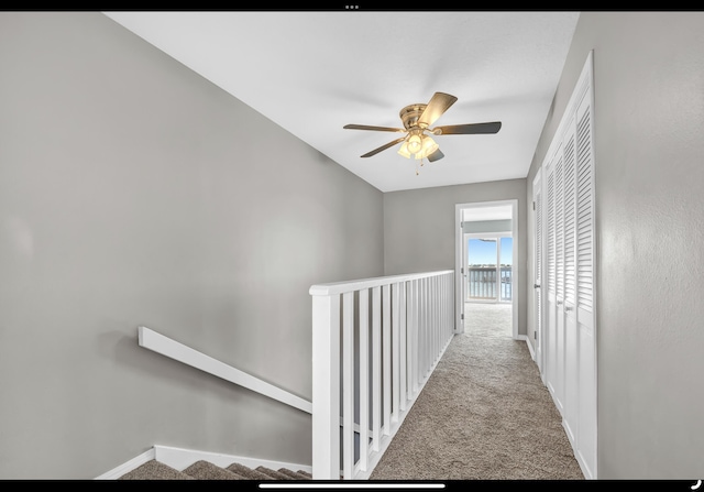 hallway featuring carpet, baseboards, and an upstairs landing