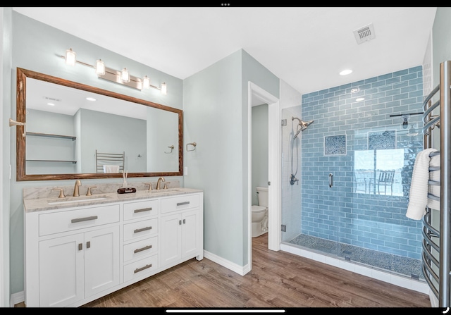 bathroom featuring a shower stall, toilet, wood finished floors, and a sink