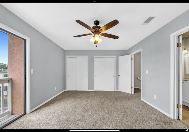 unfurnished bedroom with multiple closets, carpet floors, baseboards, ensuite bath, and visible vents