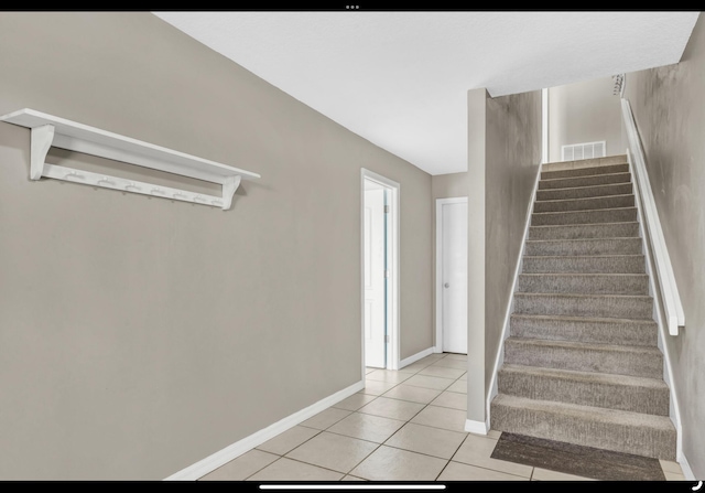 stairs with visible vents, tile patterned floors, and baseboards