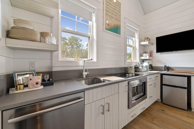 kitchen featuring stainless steel appliances, light wood-type flooring, a sink, and open shelves