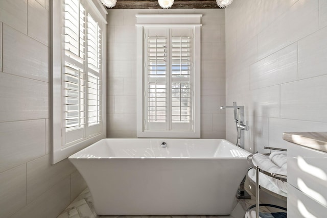 full bath with a soaking tub, plenty of natural light, and tile walls