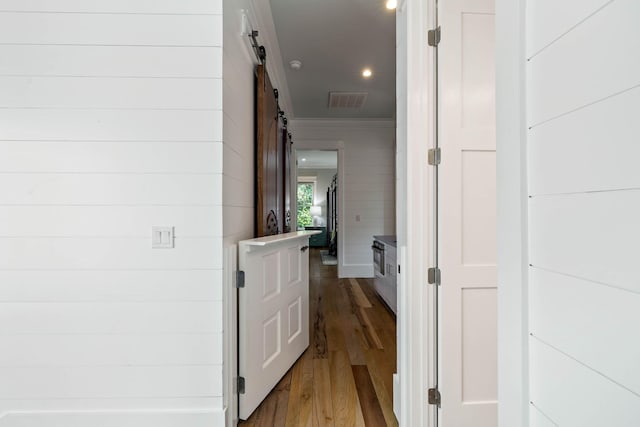 corridor featuring a barn door, wood finished floors, visible vents, and recessed lighting