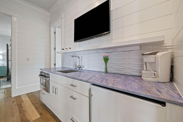 interior space featuring crown molding, light wood-style floors, stainless steel oven, a sink, and dishwasher