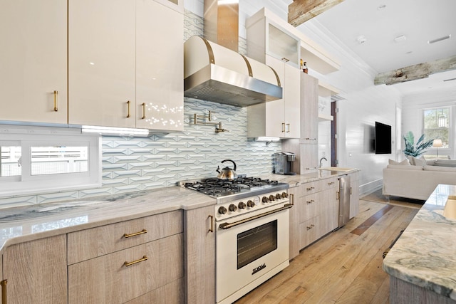 kitchen featuring open floor plan, light wood-style flooring, high end stove, and glass insert cabinets