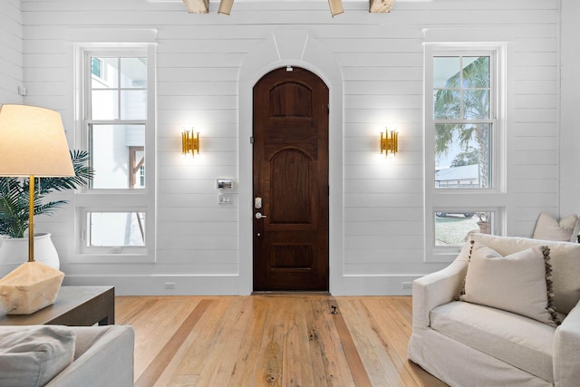 foyer entrance featuring arched walkways, plenty of natural light, and wood finished floors