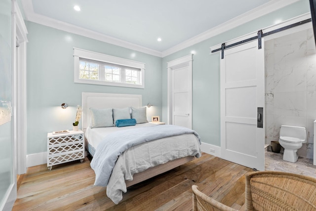 bedroom with a barn door, recessed lighting, light wood-style flooring, and crown molding