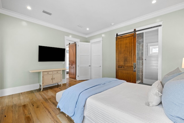 bedroom featuring visible vents, light wood-style flooring, a barn door, ornamental molding, and baseboards