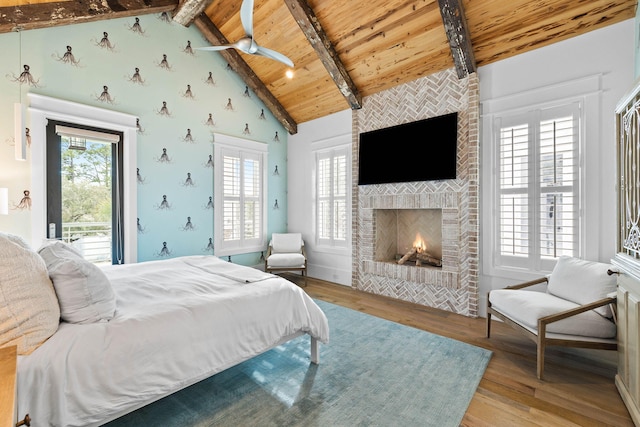 bedroom featuring wood ceiling, light wood-style floors, multiple windows, a brick fireplace, and beamed ceiling