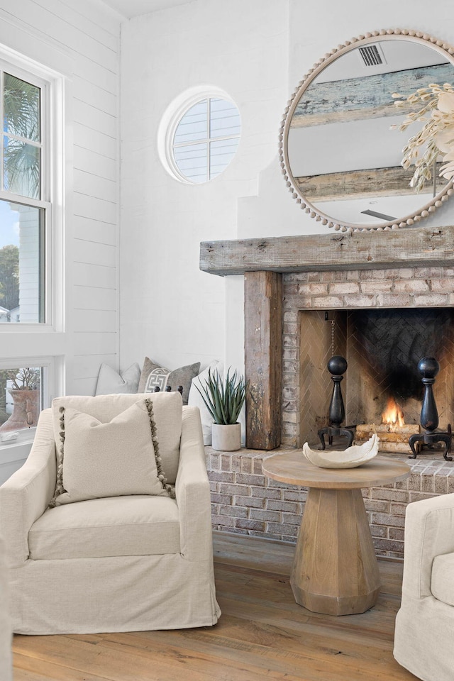 living area with plenty of natural light, wooden walls, and wood finished floors