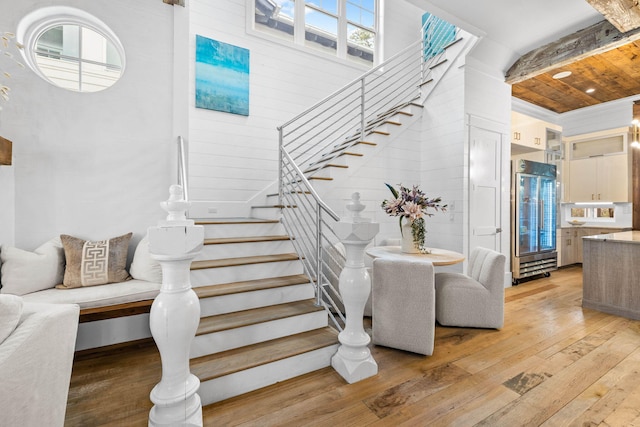 stairway with wood finished floors and beam ceiling