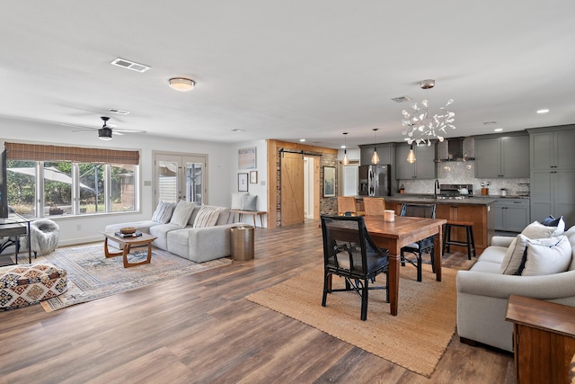 living area with dark wood-style flooring, visible vents, french doors, and a barn door