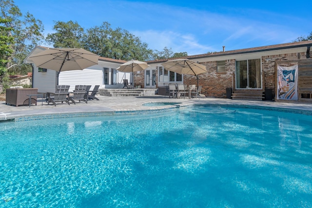 outdoor pool featuring entry steps, an in ground hot tub, and a patio area