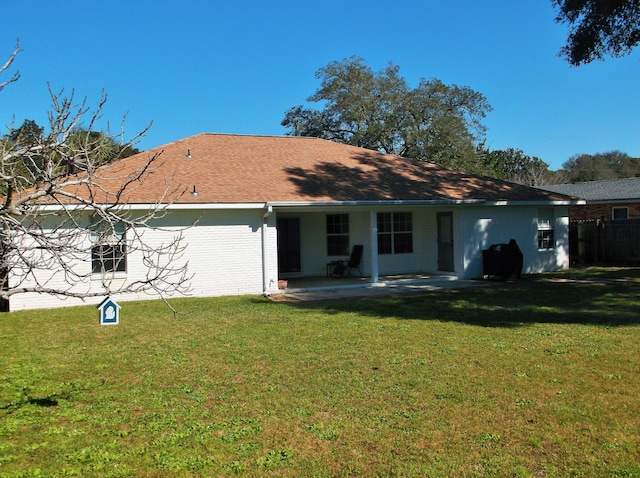 rear view of house featuring brick siding, a lawn, and a patio