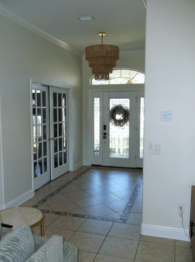 foyer with light tile patterned floors, baseboards, crown molding, french doors, and a chandelier