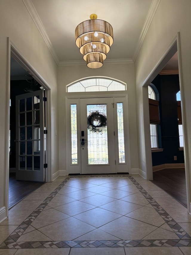 tiled foyer entrance featuring baseboards, a notable chandelier, and ornamental molding