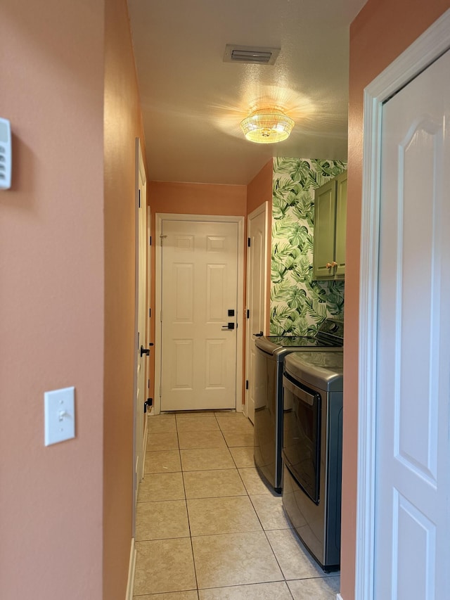 washroom with visible vents, light tile patterned flooring, washing machine and clothes dryer, and cabinet space