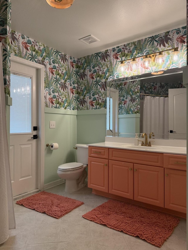 bathroom with a wainscoted wall, toilet, vanity, tile patterned flooring, and wallpapered walls