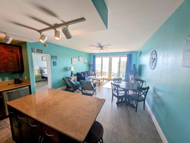 kitchen with open floor plan, baseboards, a ceiling fan, and a center island