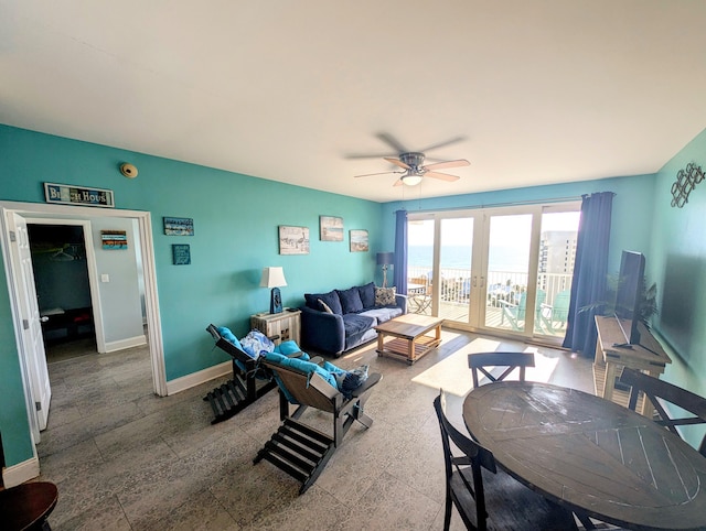 living area with a ceiling fan, french doors, and baseboards