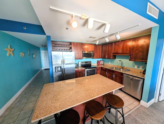 kitchen with visible vents, appliances with stainless steel finishes, a kitchen breakfast bar, a center island, and a sink