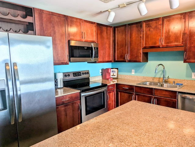 kitchen with stainless steel appliances, a sink, light stone counters, and dark brown cabinets