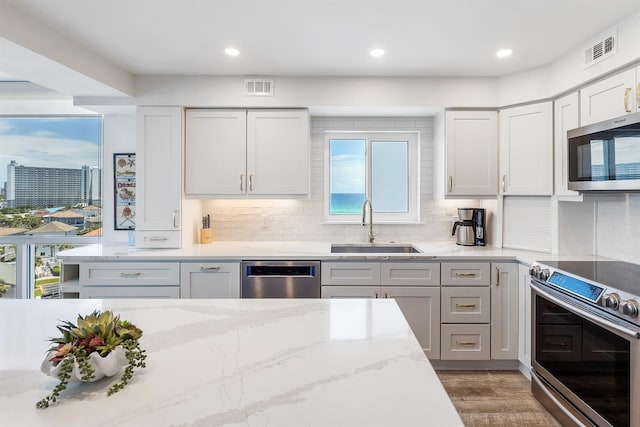 kitchen featuring appliances with stainless steel finishes, backsplash, a sink, and visible vents